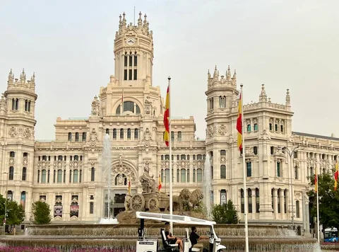 Guia bilíngue dirigindo um tuk tuk elétrico por Madrid